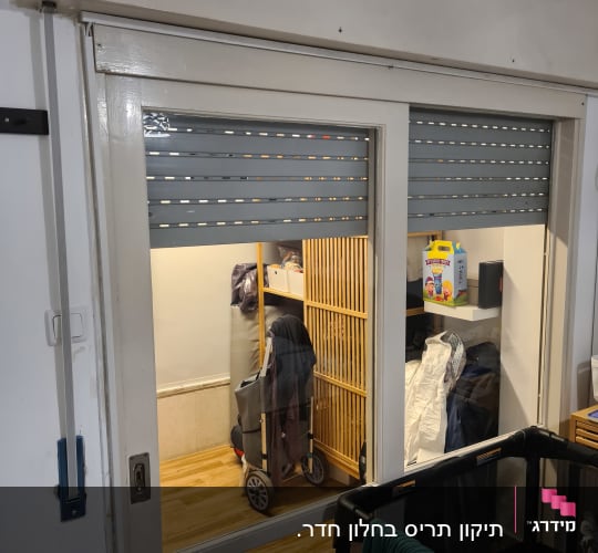 תריסים אפורים סגורים על חלון זכוכית לבן